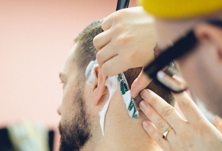 Close up photo of Jimmy Giroux giving a client a straight razor shave.